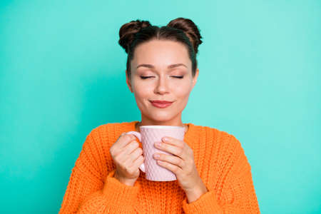 Photo of young pretty lovely charming positive smiling girl drinking enjoying tea isolated on turquoise color backgroundの写真素材