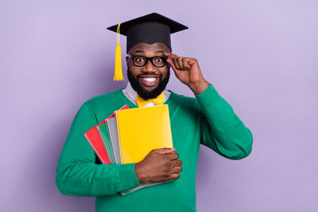Portrait of positive handsome guy hold book notebook touch eyeglasses isolated on purple color backgroundの写真素材