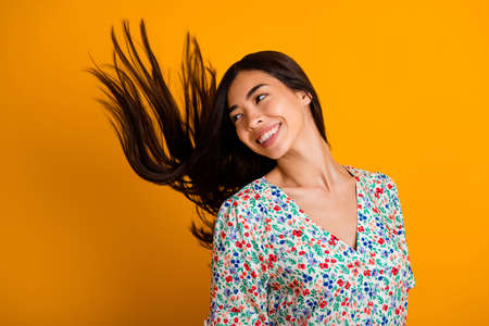 Photo of cheerful pretty girl toothy smile look empty space flying black hairdo isolated on yellow color backgroundの写真素材