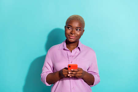 Photo of minded nice person hold telephone look interested empty space isolated on turquoise color...