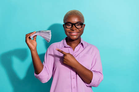 Photo of successful person indicate finger dollars profit banknotes isolated on turquoise color...