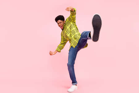 Full body photo of cheerful crazy afro american man raise leg fighter isolated on pastel pink color...