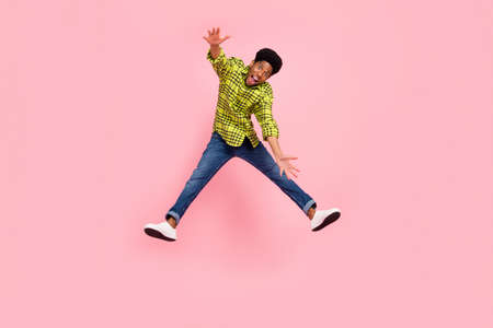 Full length photo of young funny brunette guy jump wear shirt jeans sneakers isolated on pink...