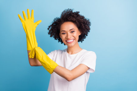 Portrait of attractive cheerful girl wearing rubber gloves tidy up service isolated over bright blue color backgroundの写真素材