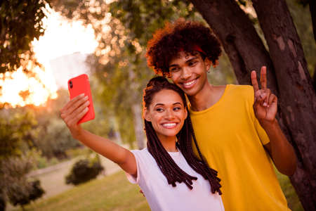 Portrait of handsome beautiful cheerful couple taking making selfie showing v-sign having fun at...