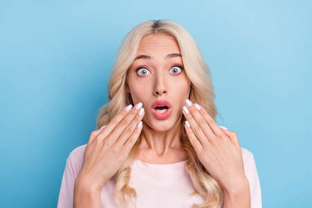 Photo portrait blonde woman curly hair staring amazed bad news isolated pastel blue color backgroundの写真素材