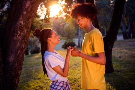 Profile side view portrait of attractive affectionate cheerful couple holding hands spending honey...