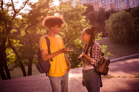 Portrait of attractive cheerful couple best friends spending weekend sunny evening talking chatting outdoorsの写真素材