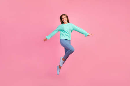 Full length portrait of excited cheerful person arms wings flying jumping isolated on pink color backgroundの写真素材