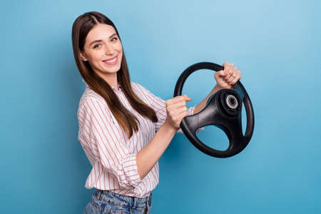 Profile side view portrait of attractive cheerful girl holding steering wheel isolated over shine blue color backgroundの写真素材