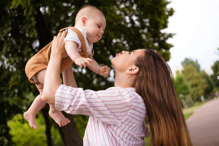 Photo of lovely sweet mom hold her baby kiss enjoy countryside trip outside city town wear casual clothesの写真素材