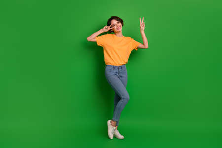 Full size portrait of gorgeous nice lady arms fingers demonstrate v-sign near eye isolated on green...