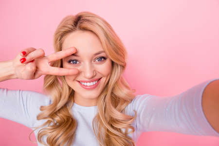 Photo of funky pretty girl make selfie hand fingers demonstrate v-sign isolated on pink color backgroundの写真素材
