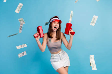 Photo of young pretty joyful woman good mood hold hand gun shoot money win isolated on blue color...