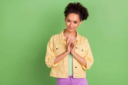 Photo of pretty millennial brunette lady hold hands wear yellow shirt isolated on green color...