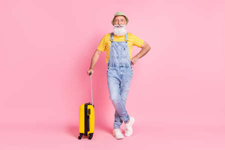 Full length body size view of attractive cheerful man holding bag isolated over pink pastel color...