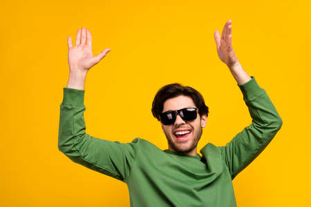 Photo of young cheerful happy positive cool man wear sunglass dance enjoy isolated on yellow color backgroundの写真素材