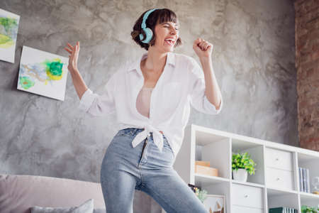 Portrait of attractive funny cheerful girl listening melody pretending singing hit single having fun at home loft interior indoorsの写真素材
