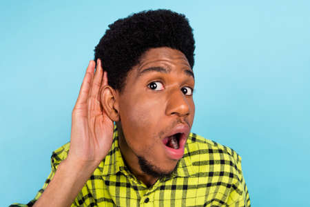 Photo of millennial brunette curious guy hand ear wear yellow shirt isolated on blue color backgroundの写真素材