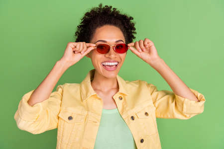 Photo of cool young brunette lady wear yellow shirt eyewear isolated on green color backgroundの写真素材