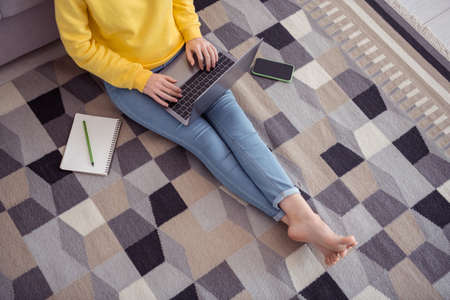 Above view cropped photo of busy person sitting carpet use wireless netbook house indoorsの写真素材