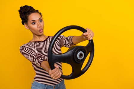 Photo of impressed young lady arms hold wheel look empty space pouted lips isolated on yellow color...
