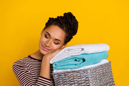 Photo of adorable positive girl closed eyes hold enjoy fresh laundry isolated on yellow color backgroundの写真素材