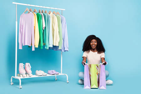 Full length photo of pretty positive girl sit floor hold shop delivery packages isolated on blue...