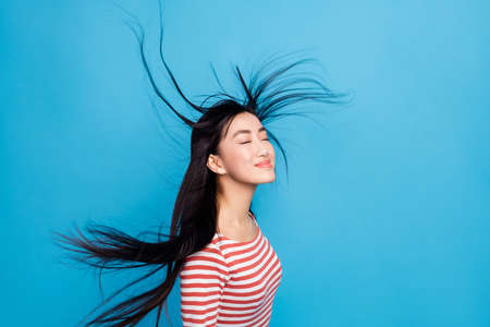 Photo of shiny lovely lady dressed red shirt enjoying wind blowing isolated blue color backgroundの写真素材