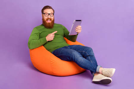 Full body portrait of astonished crazy person direct finger tablet isolated on purple color backgroundの写真素材