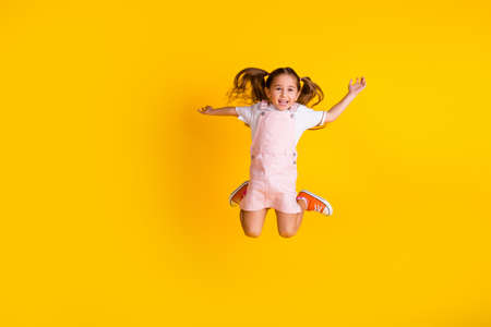 Photo of funky excited preschool lady dressed pink clothes jumping high empty space isolated yellow color backgroundの写真素材