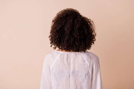 Photo of stunning curly wavy lady wear white top standing back isolated beige color backgroundの写真素材
