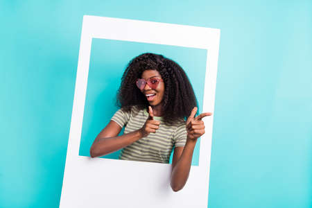 Photo of funny sweet lady wear striped t-shirt dark glasses tacking photo pointing you empty space isolated turquoise color backgroundの写真素材