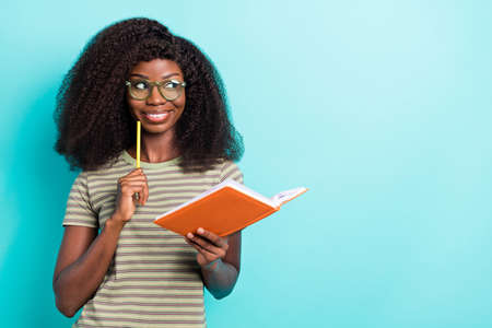 Portrait of cheerful nice lady hold diary pen look interested empty space hmm deep isolated on shine cyan color backgroundの写真素材