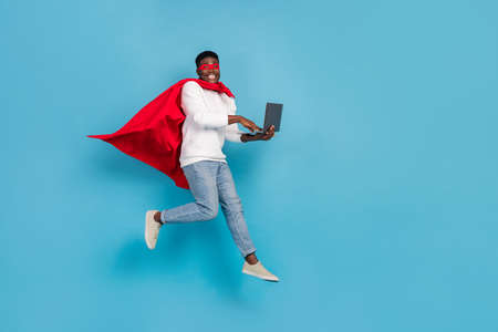 Full body portrait of handsome guy red cloak use wireless netbook digital connection isolated on blue color backgroundの写真素材