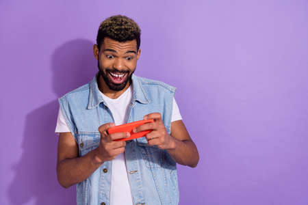 Photo of excited pretty man wear jeans waistcoat playing game modern gadget empty space isolated...