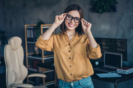 Portrait of attractive intelligent cheerful girl expert touching specs developing web project at...
