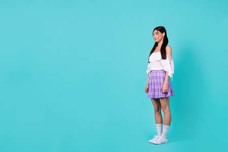 Full length photo of gorgeous nice thai girl standing look empty space isolated on bright teal color backgroundの写真素材