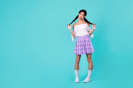 Full length photo of minded pretty thai person arms hold touch black tails look empty space isolated on emerald color backgroundの写真素材