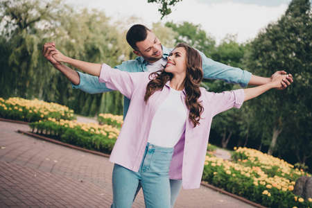 Portrait of two lovely cheerful people hold hands dancing have good mood enjoy nice weather outdoorsの写真素材