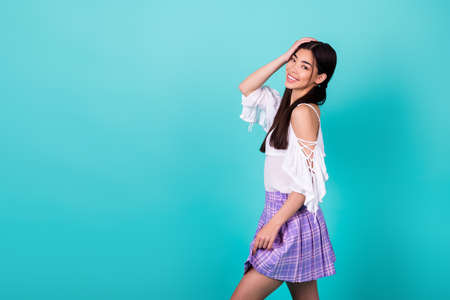 Profile photo of stunning positive malaysian person hand touch hair skirt empty space isolated on vibrant cyan color backgroundの写真素材