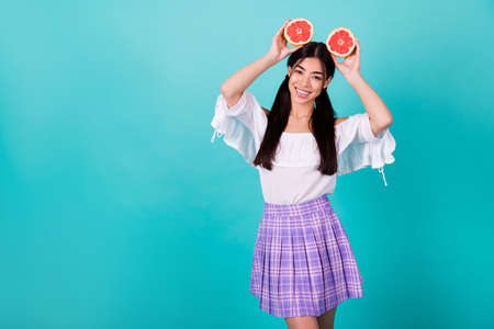 Photo of dreamy cute lady wear white holding two orange halves head empty space isolated turquoise color backgroundの写真素材
