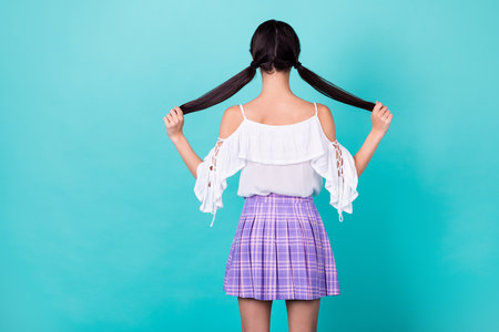 Photo of slim skinny lady wear white top standing back holding tails empty space isolated turquoise color backgroundの写真素材