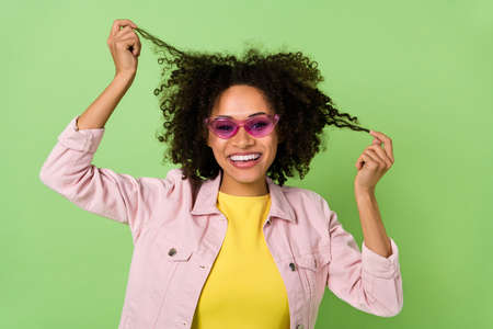 Photo of adorable funny lady wear pink denim jacket eyewear holding arms curls isolated green color...
