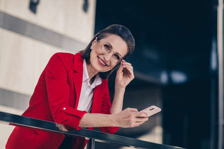 Photo of positive modern age lady economist recruiter stand outdoors cityscape use gadget typing letter wear suitの写真素材