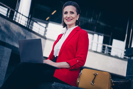 Photo of smart economist programmer aged lady typing email partners use device netbook outside workplaceの写真素材
