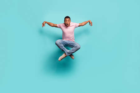 Full length photo of funky cool man dressed pink t-shirt practicing karate jumping high isolated turquoise color backgroundの写真素材