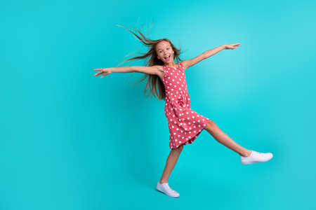 Photo of adorable excited small girl wear pink dress walking smiling wind blowing isolated turquoise...