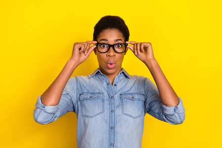Photo of impressed person pouted lips hands touch eyeglasses unbelievable isolated on yellow color backgroundの写真素材