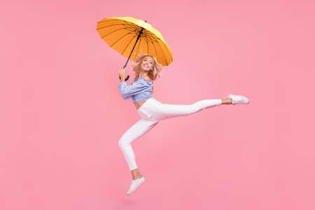 Full length photo of dreamy sweet girl dressed blue top jumping high holding umbrella isolated pink color backgroundの写真素材